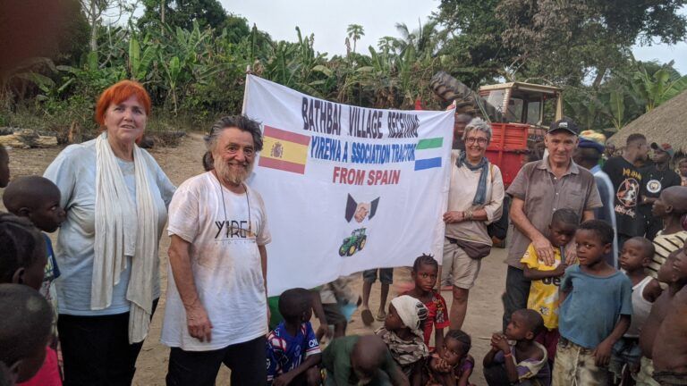 Voluntarios junto a una pancarta de bienvenida